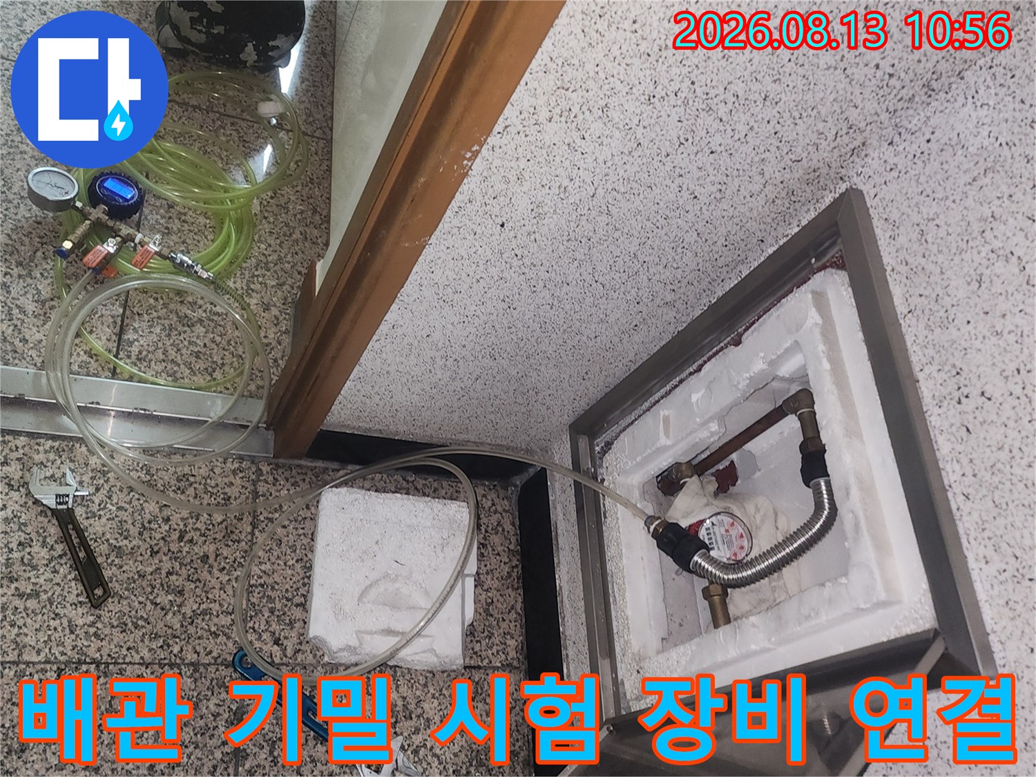 흰색 단열재가 있는 배관 점검구와 바닥의 다양한 누수 탐지 도구들 사진