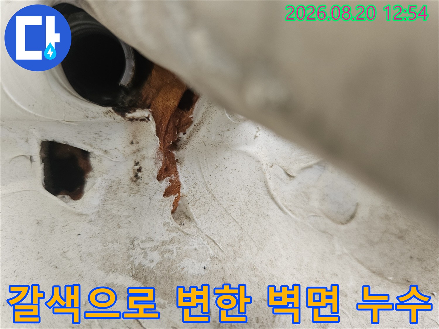 우수관 배관 주변의 갈색 누수 오염과 젖은 마감재