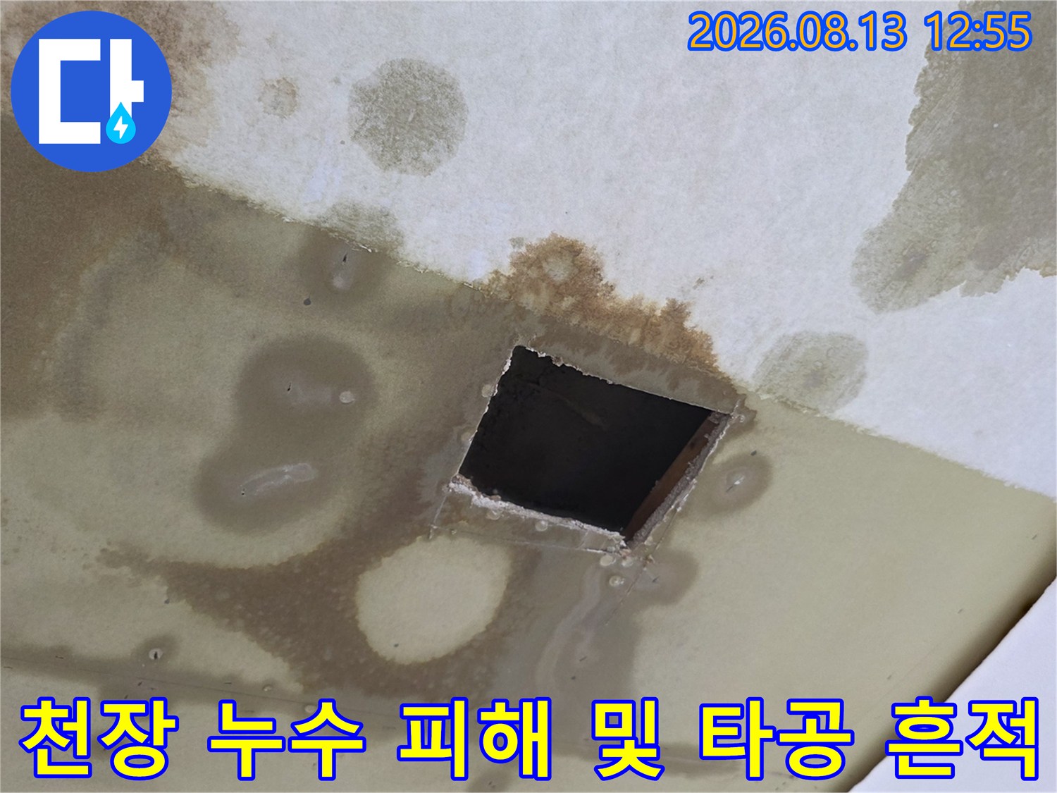 물에 젖어 갈색으로 변한 천장지 표면과 중앙의 검은 사각형 구멍