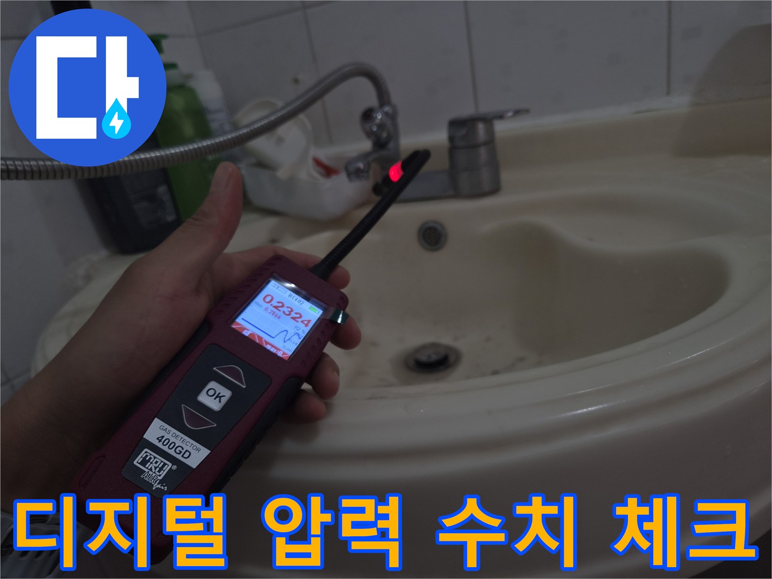 세면대 아래 배관에 연결된 디지털 압력계의 숫자를 보는 장면