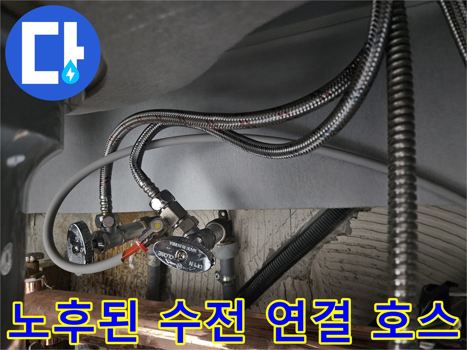 금속 재질의 꼬임형 호스와 급수 밸브가 설치된 싱크대 하부 배관 모습