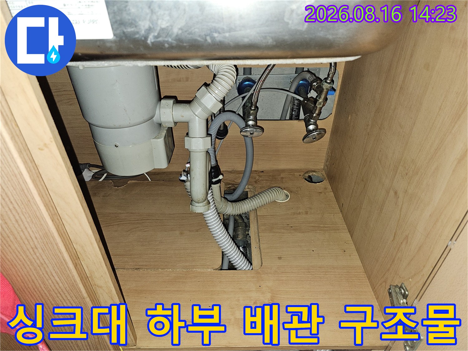 싱크대 하부장 내부의 급수 밸브와 배수 호스 사진