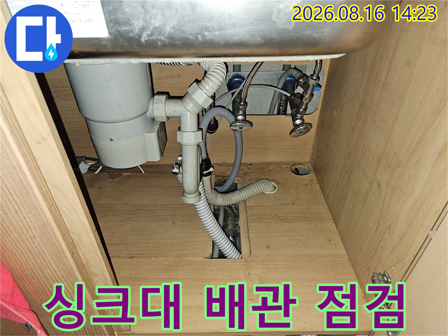 싱크대 하부장 내부의 배관 연결 상태를 확인하는 장면입니다.