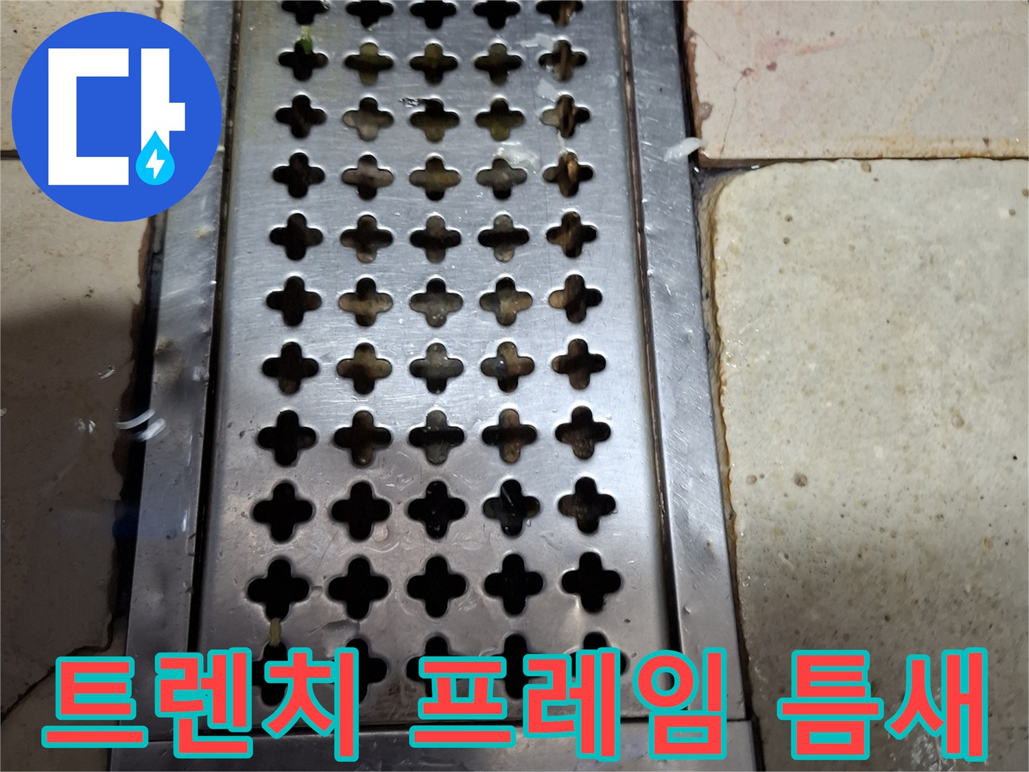 배수구 금속 판과 타일 사이의 벌어진 간격을 촬영한 사진입니다.