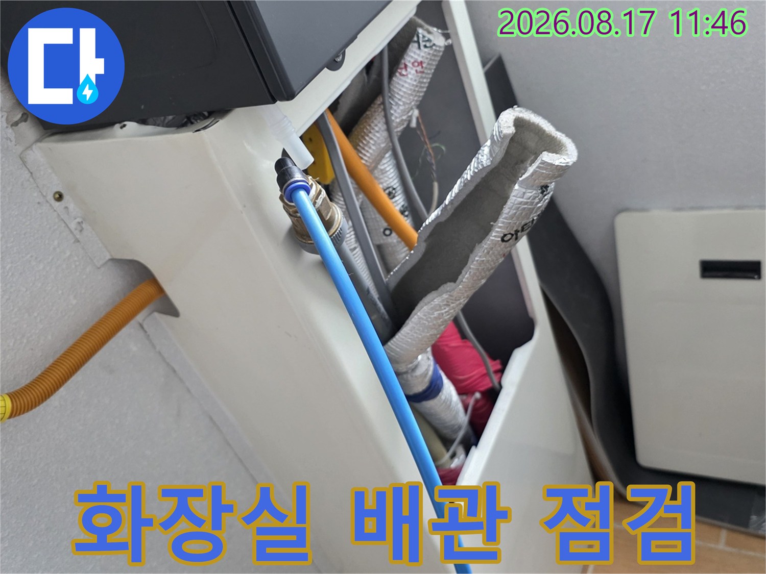 은박 보온재와 파란색 급수 호스가 복합적으로 연결된 배관 구조물 사진