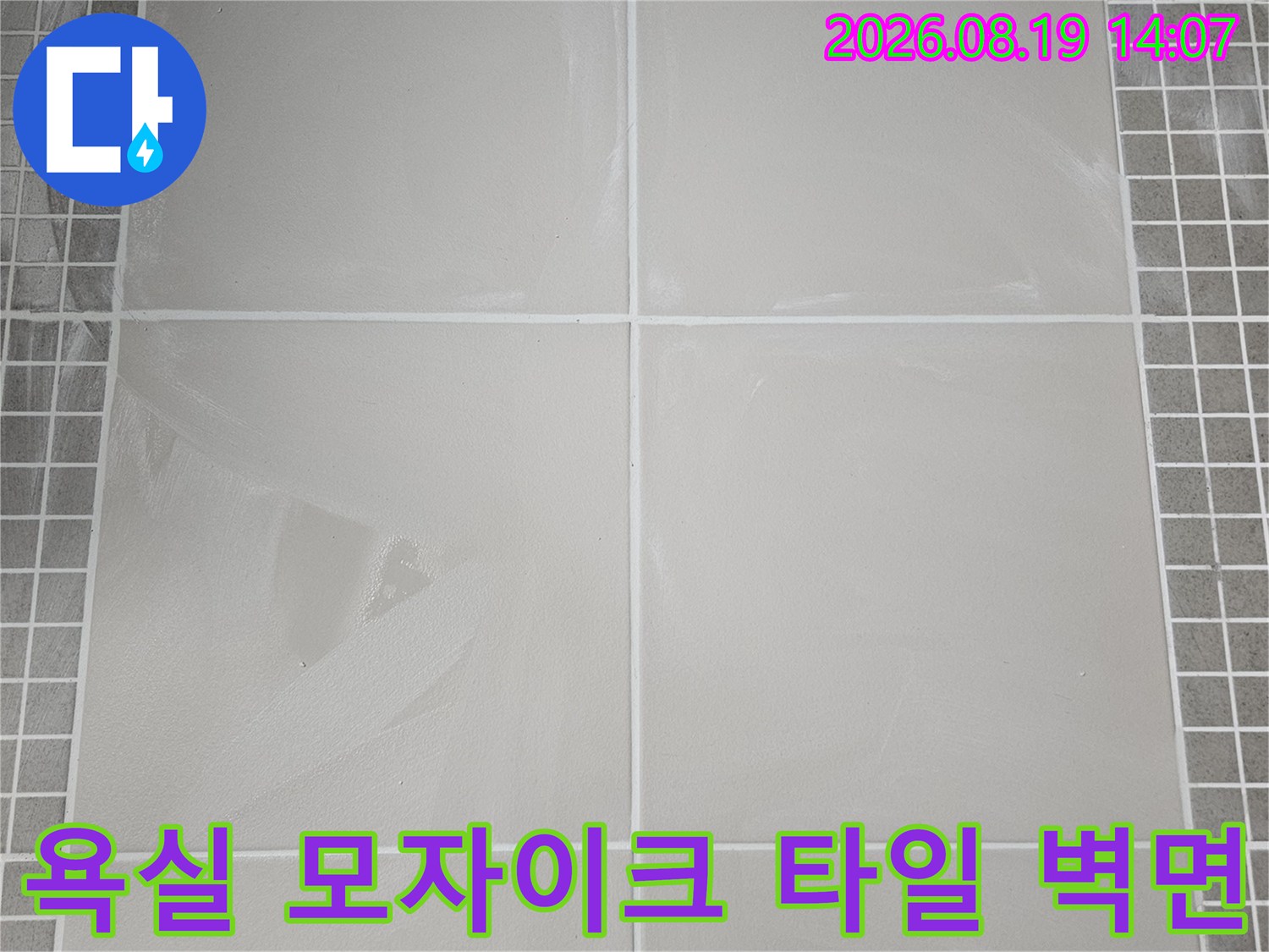 밝은 색상의 대형 타일과 작은 격자 무늬 타일이 만나는 욕실 내부 벽면