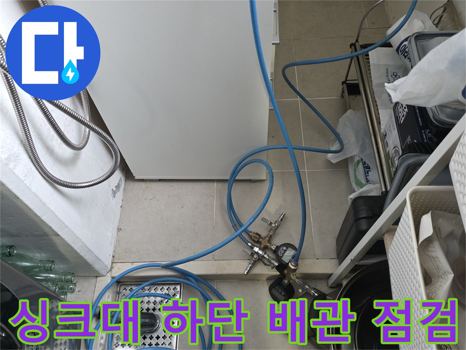 싱크대 아래 정수기 호스와 배수관의 누수 여부를 확인하는 검사 장면