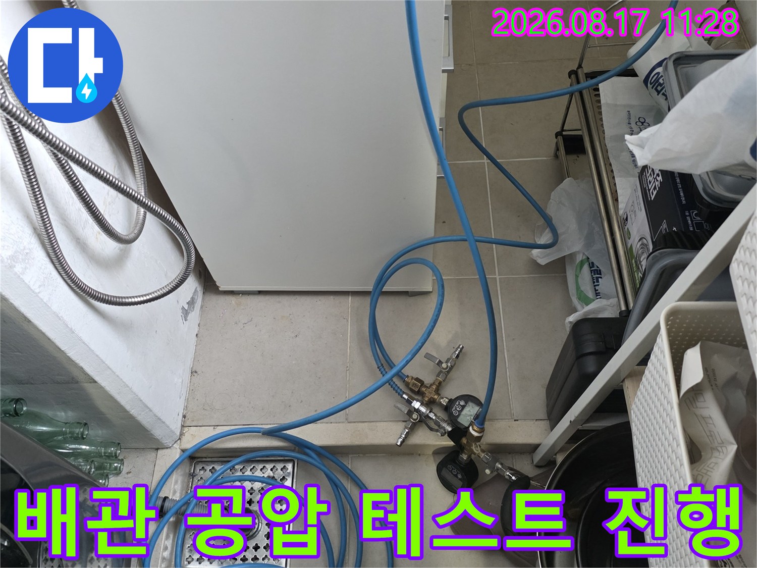 싱크대 하부 배수구 근처에 설치된 누수 탐지용 압력 게이지와 호스