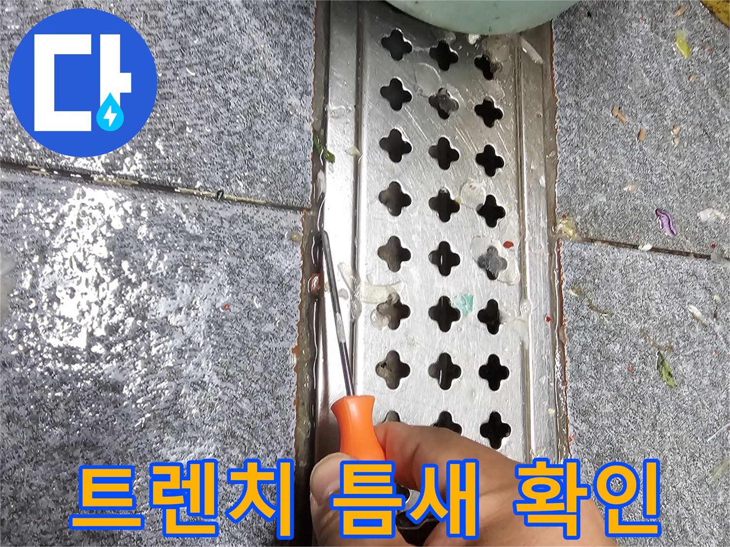 배수 트렌치 격자 틈새를 드라이버로 짚어가며 점검하는 현장 사진