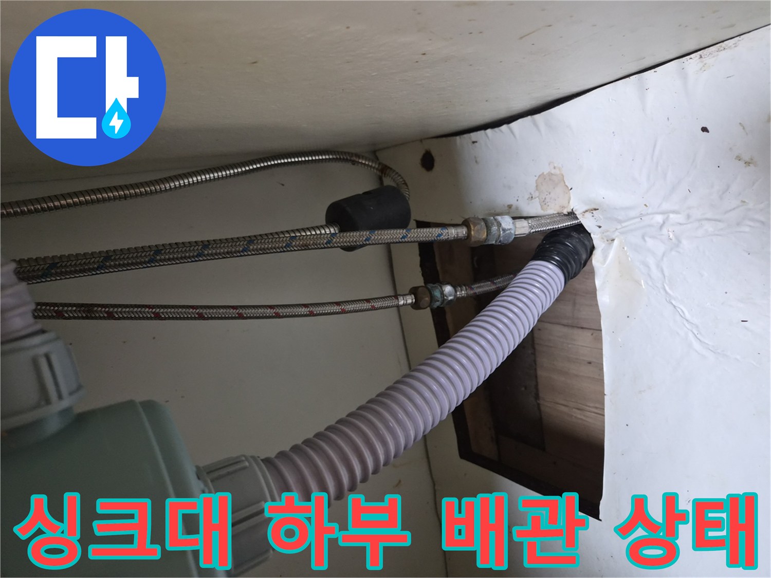 싱크대 아래쪽 좁은 공간에 연결된 은색 고압 호스와 급수 관로