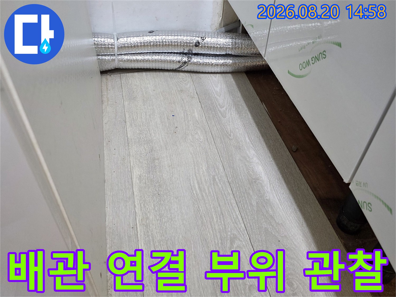 바닥 마감재 주변의 보일러 배관 연결 상태를 확인하는 장면입니다.