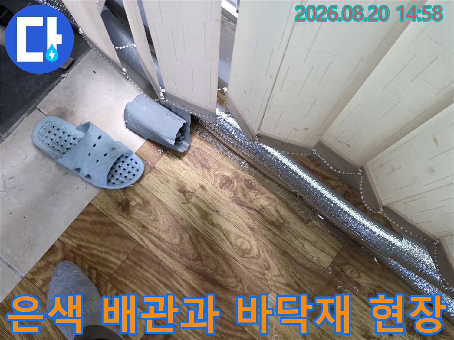 보일러 배관의 보온재 마감 상태와 나무 바닥의 근접 촬영 사진입니다.