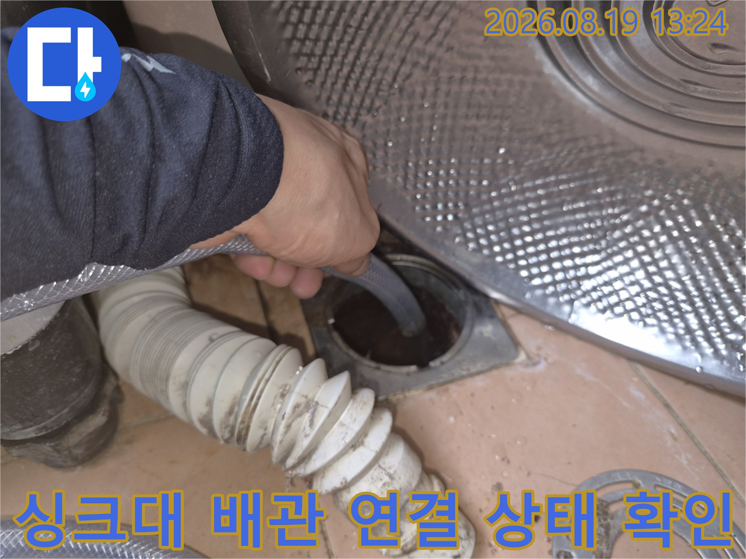 싱크대 하부장 내부의 배관 연결 부위를 엔지니어가 직접 점검하고 있습니다.