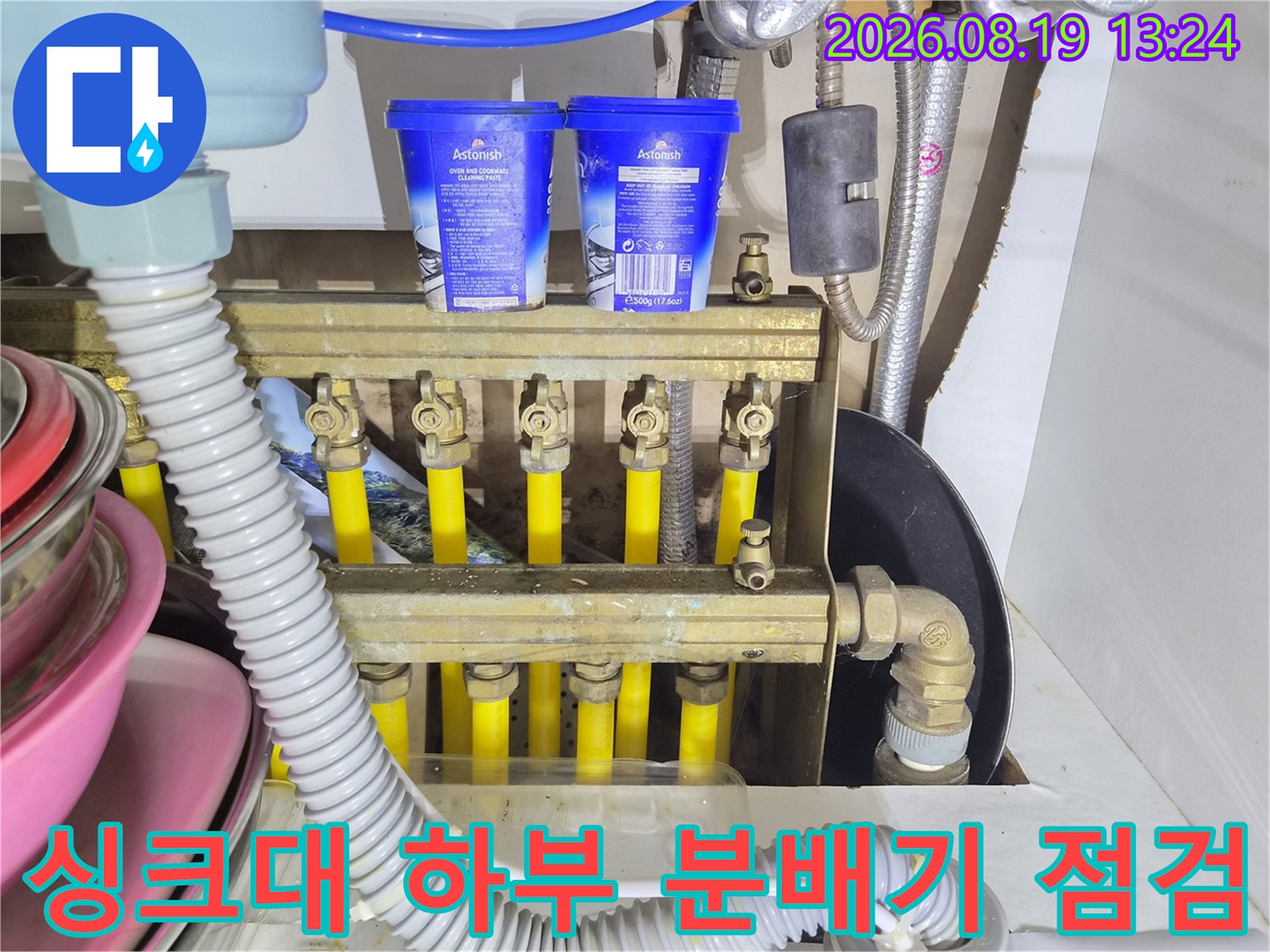싱크대 하부장에 설치된 보일러 분배기와 배관 연결 부위 모습입니다.