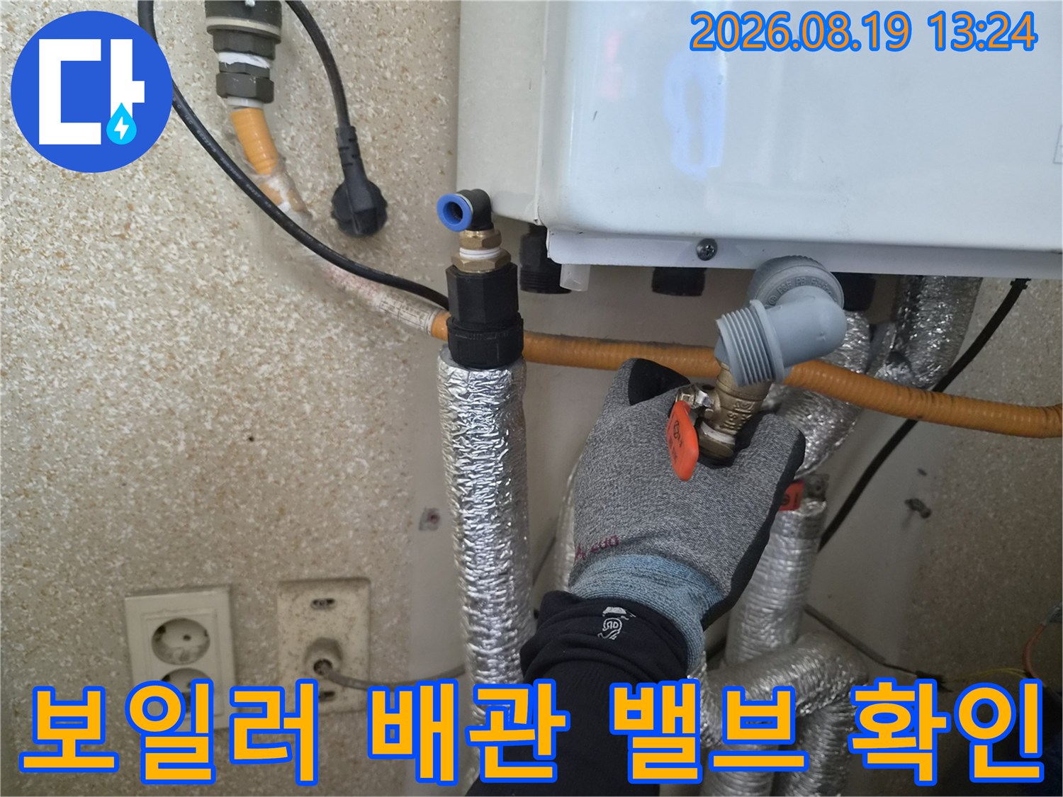 엔지니어가 보일러 하단의 밸브와 연결된 배관을 직접 점검하고 있습니다.