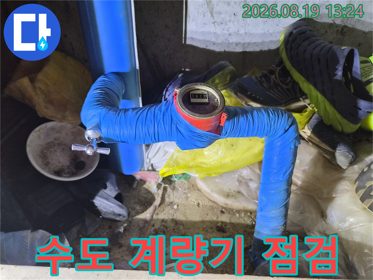 파란색 보온재로 감싸진 수도 배관과 디지털 계량기 장치입니다.