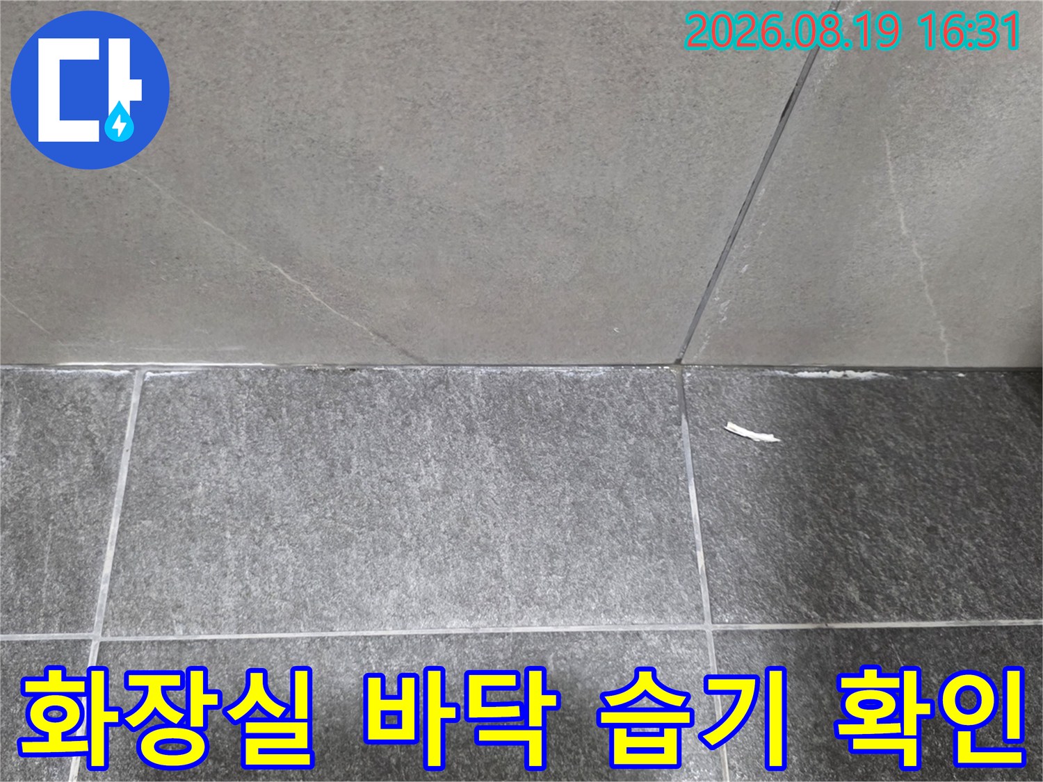 세면대 하단 타일 틈새와 벽면 경계 부위의 누수 흔적을 촬영한 사진입니다.