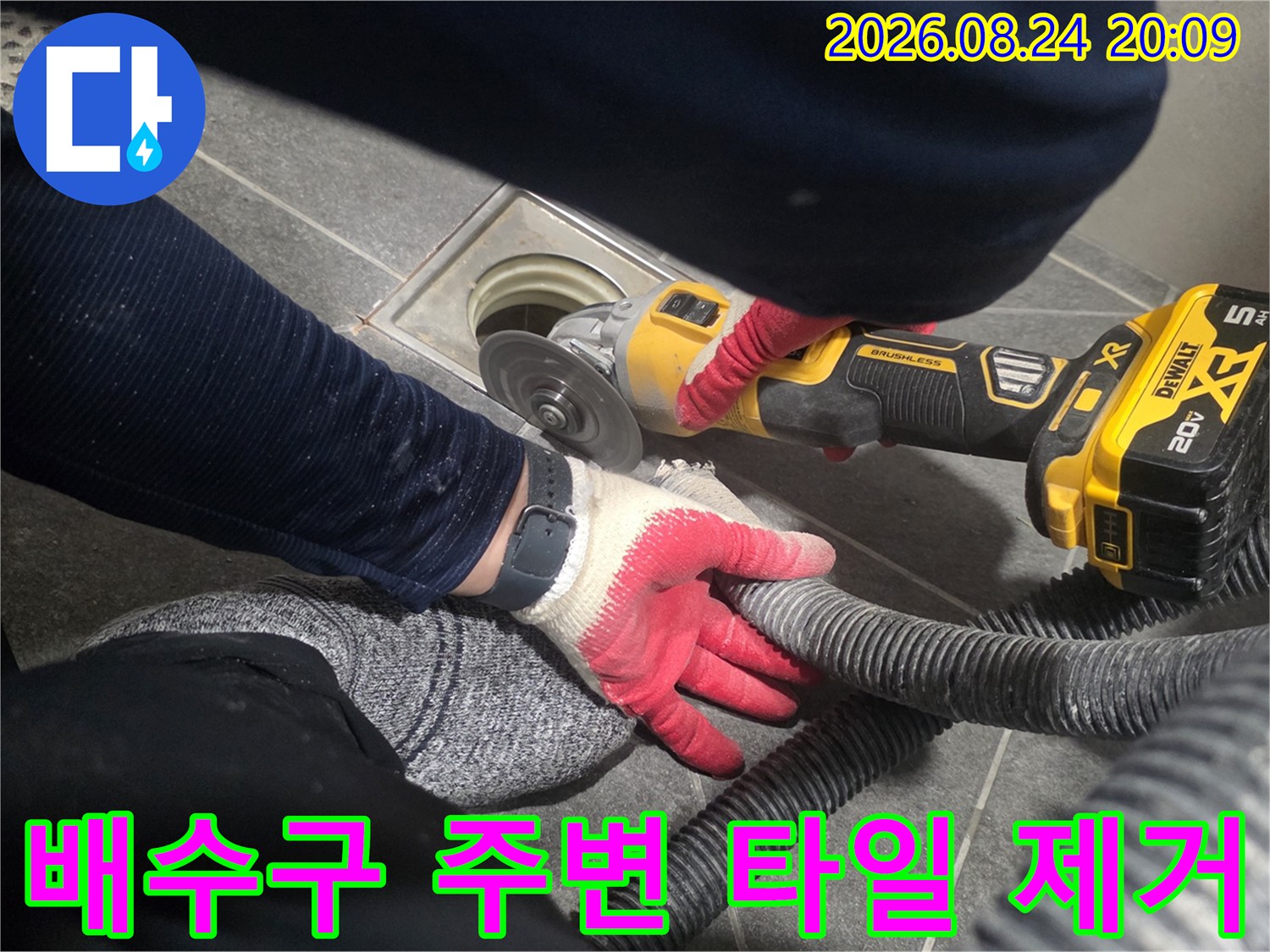 그라인더를 이용해 배수구 유가 근처의 타일을 제거하는 작업 장면입니다.