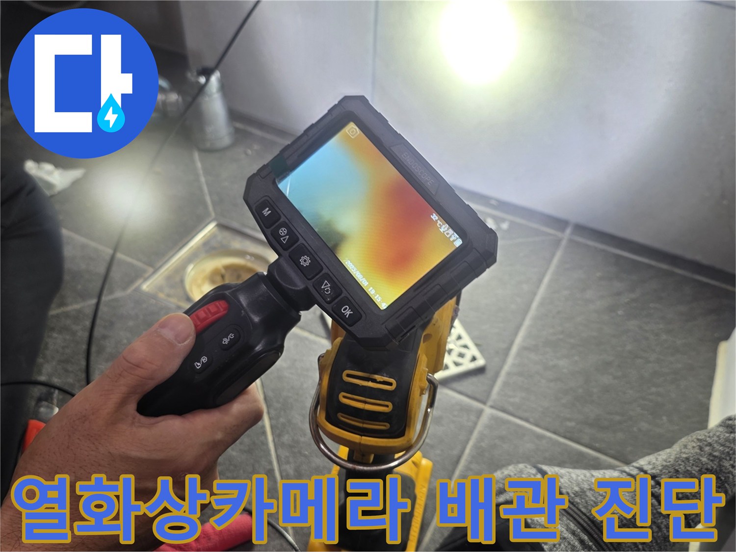 열화상 카메라를 사용하여-욕실 배수구 주변의 온도 차이를 확인하며-배관 내부 상태를 정밀하게 점검하는 모습