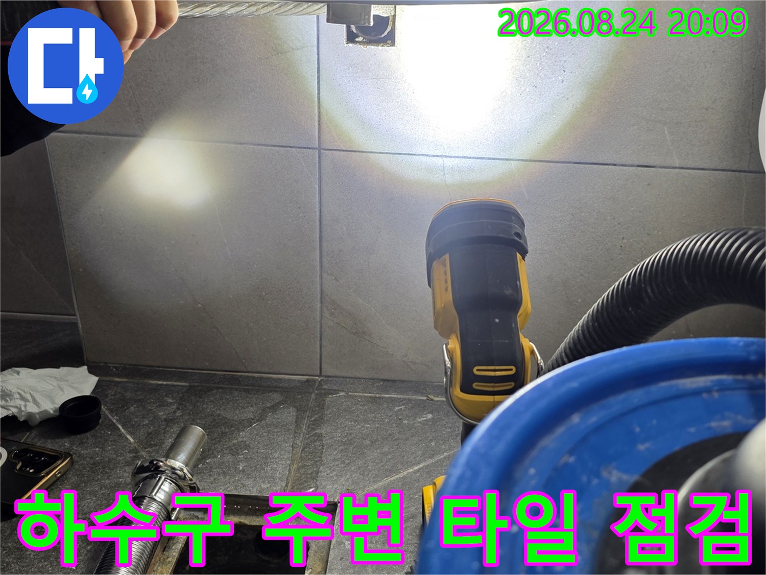 조명을 비추며 배수구 유가 주변의 타일 틈새를 관찰하는 엔지니어의 손길입니다.