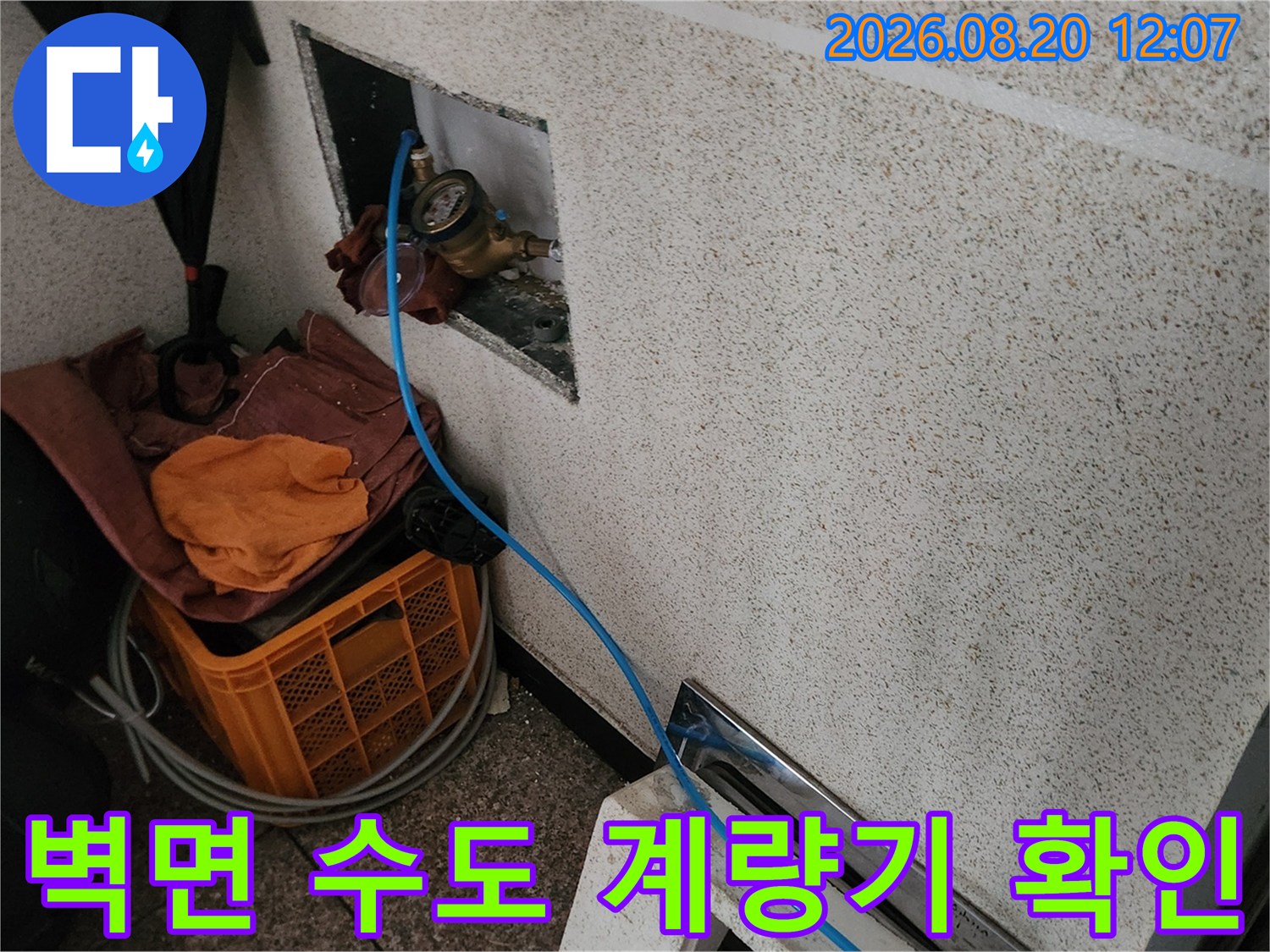 벽 안쪽 공간에 설치된 수도 계량기와 연결 배관의 모습입니다.