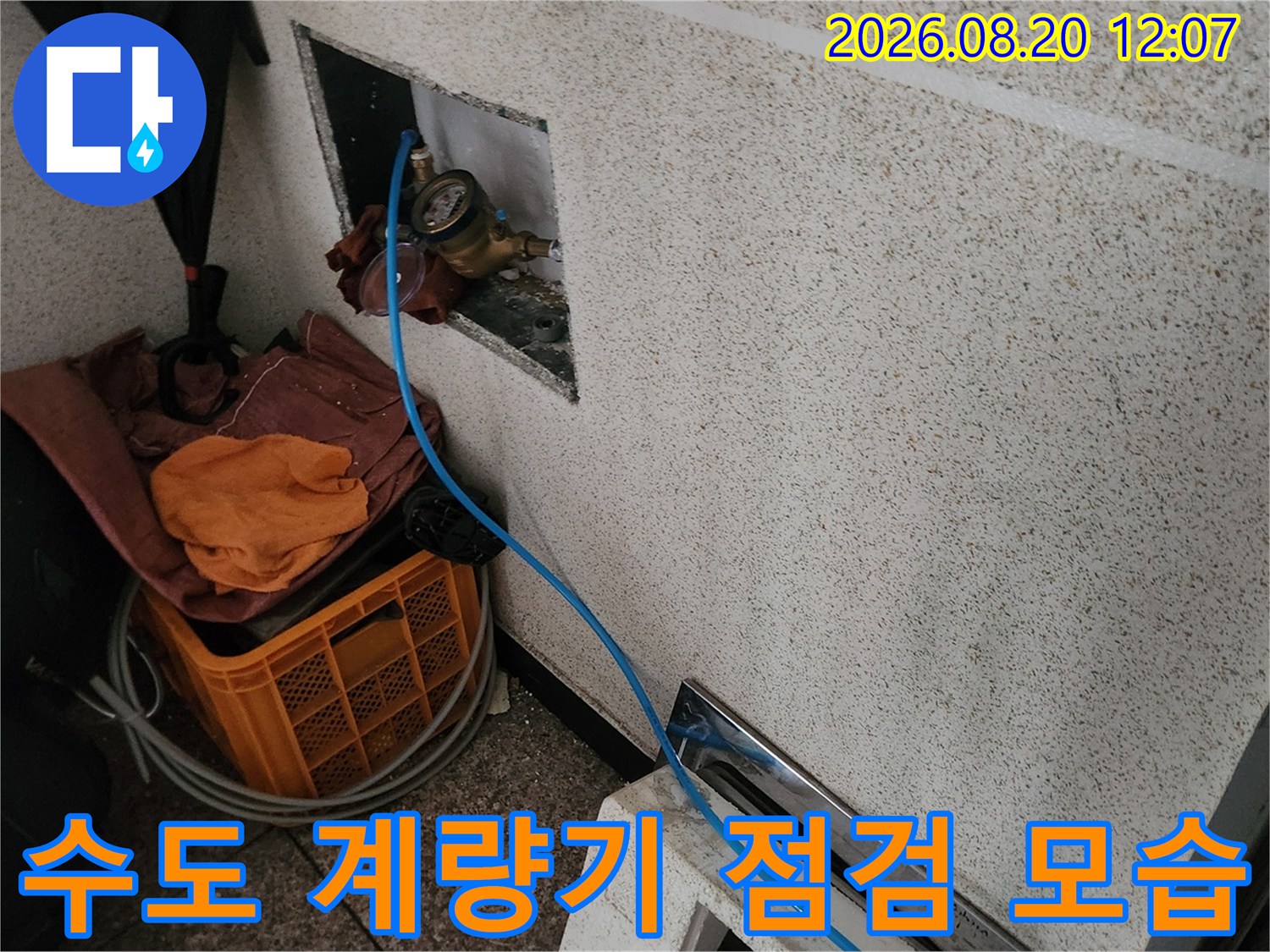 벽면 함 내부에 위치한 수도 계량기와 점검용 호스