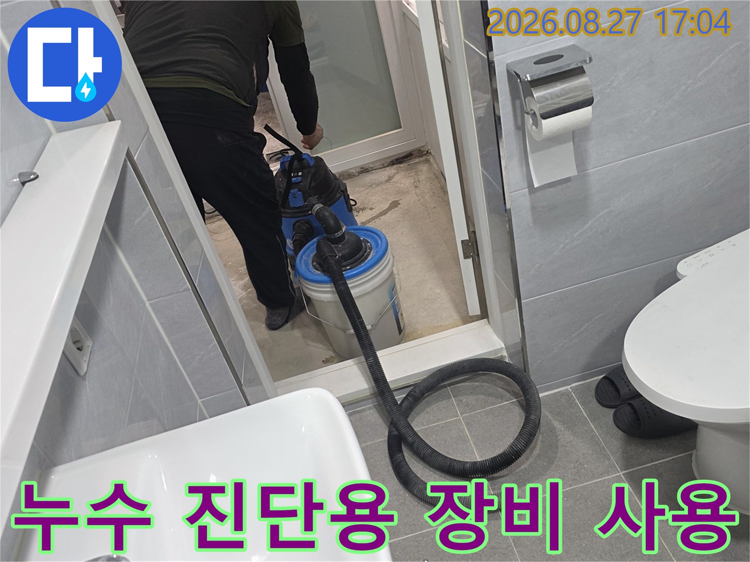 엔지니어가 화장실 바닥의 습기를 제거하며 누수 지점을 찾기 위해 집중하는 모습입니다.