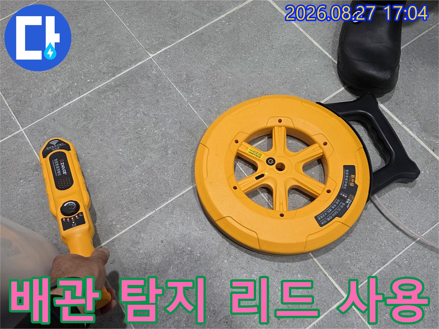 회색 타일 사이의-누수 지점을 찾기 위해-탐지기를 조작하는 모습입니다