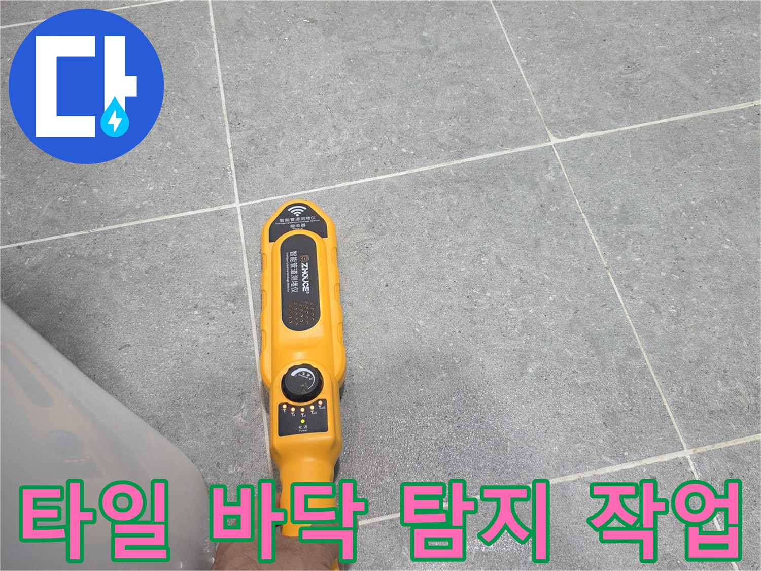 회색 타일 위에서-누수 지점을 찾기 위해 탐지기를 작동시키는 모습입니다.