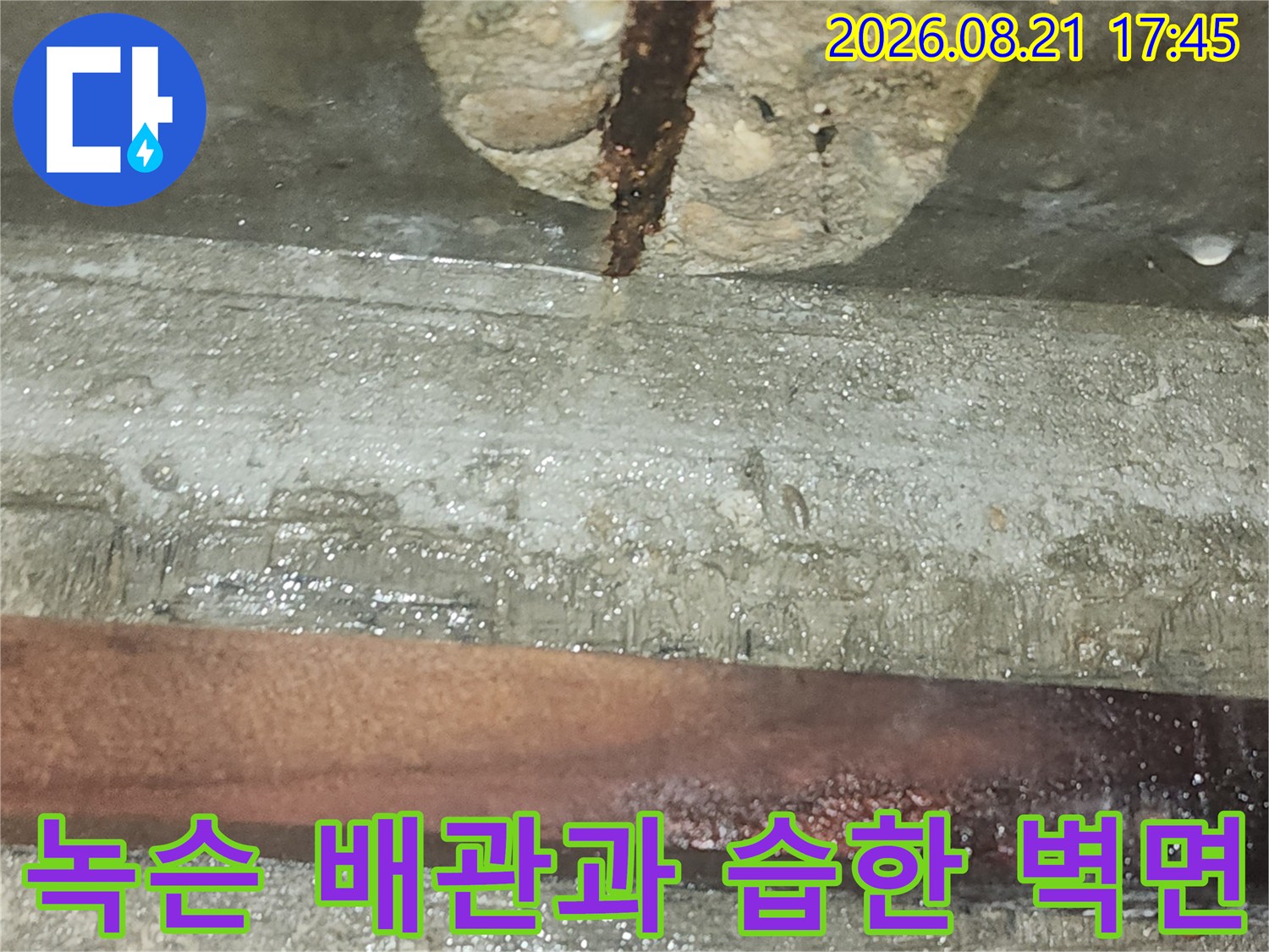 붉게 부식된 배관과 습기를 머금은 콘크리트 구조물의 근접 촬영 사진입니다.