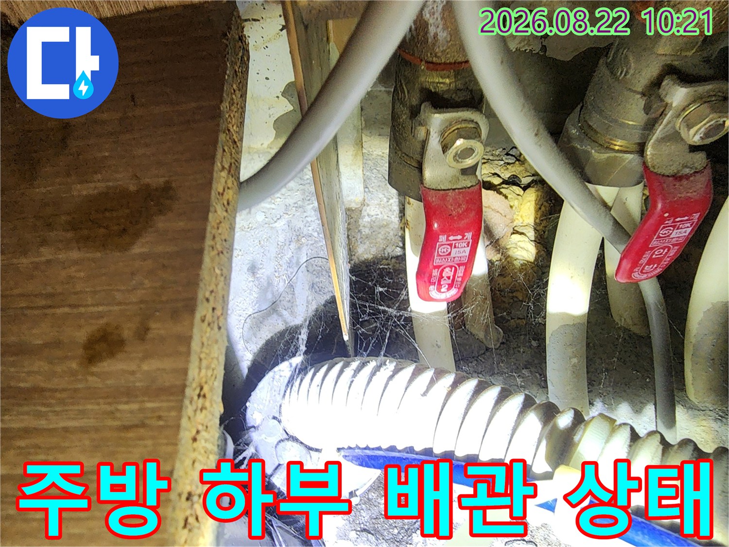 싱크대 밑 급수 밸브와 흰색 배수 호스의 연결 구조