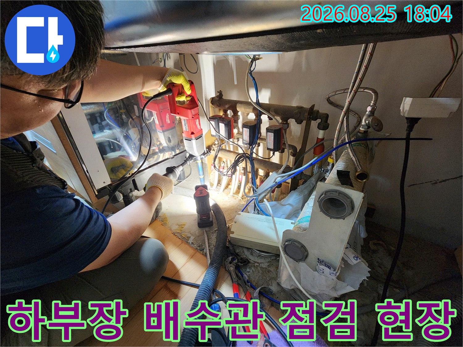 복잡한 주방 배관 사이에서 누수 지점을 찾기 위해 장비를 활용하여 정밀하게 조사하는 장면입니다.