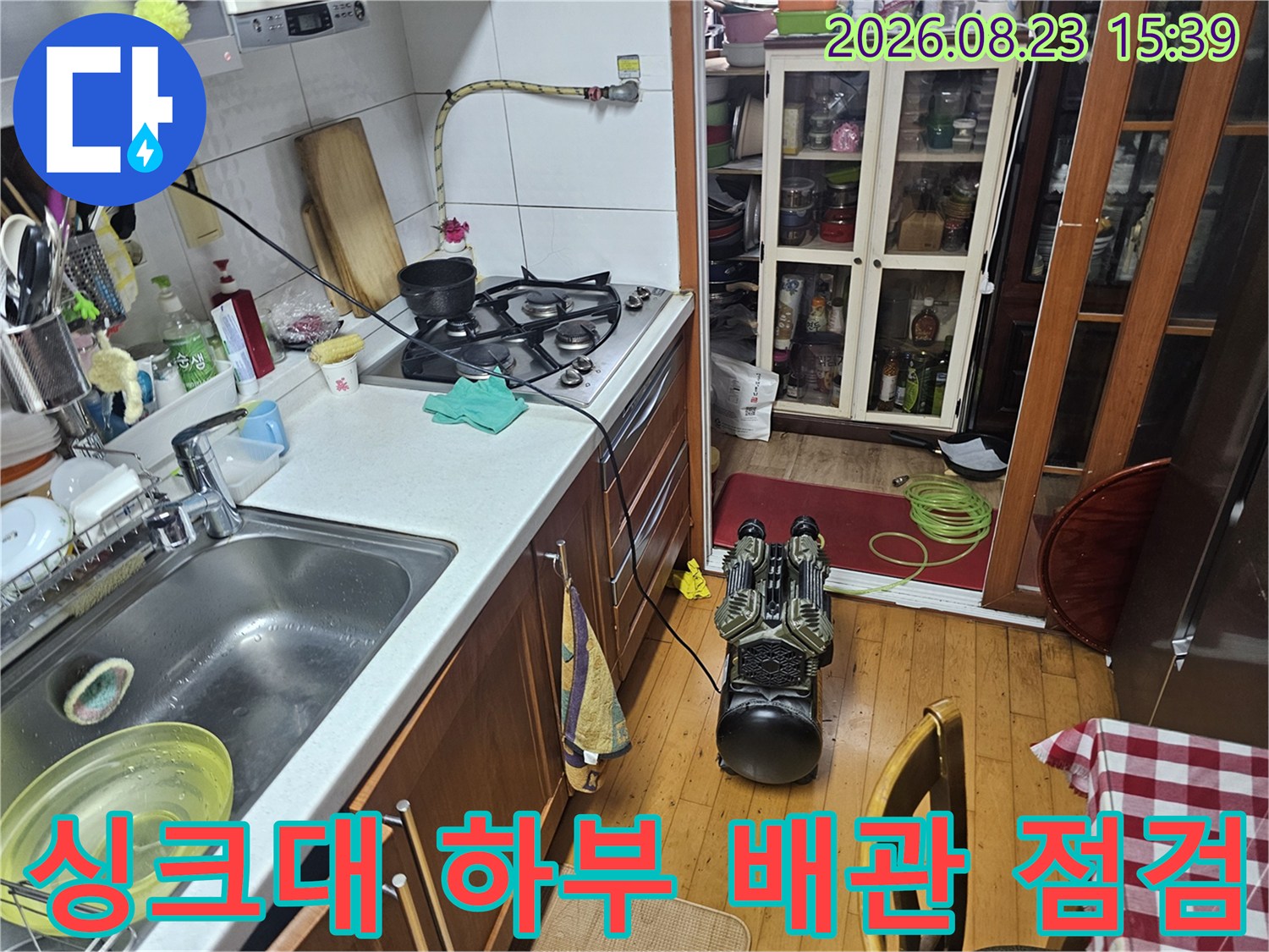 싱크대 아래쪽 공간의 배관 연결 부위와 가스 호스를 상세히 관찰하는 장면입니다.