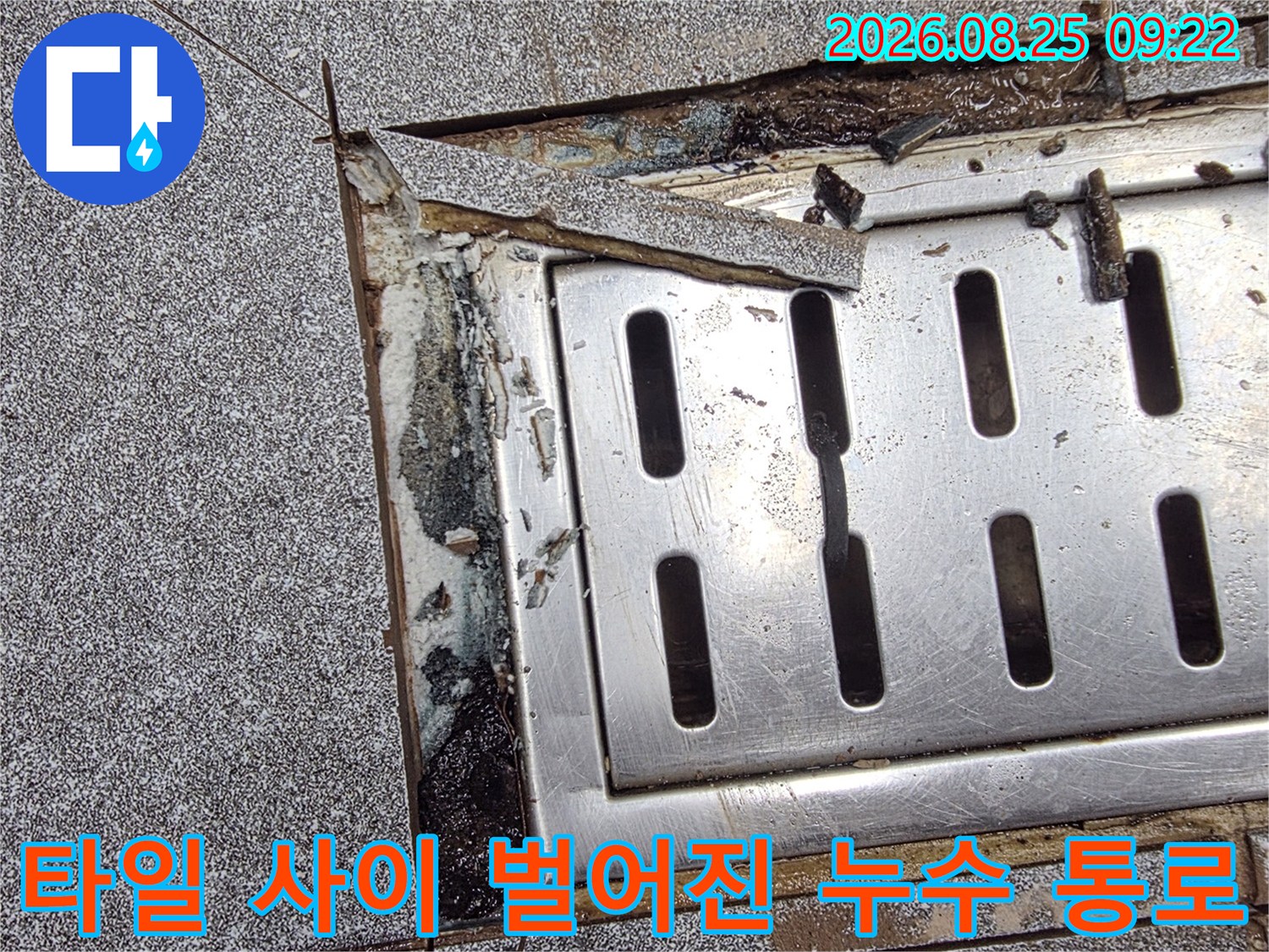 금속 배수 트렌치 주변의 타일 균열과 누수 흔적을 찍은 사진