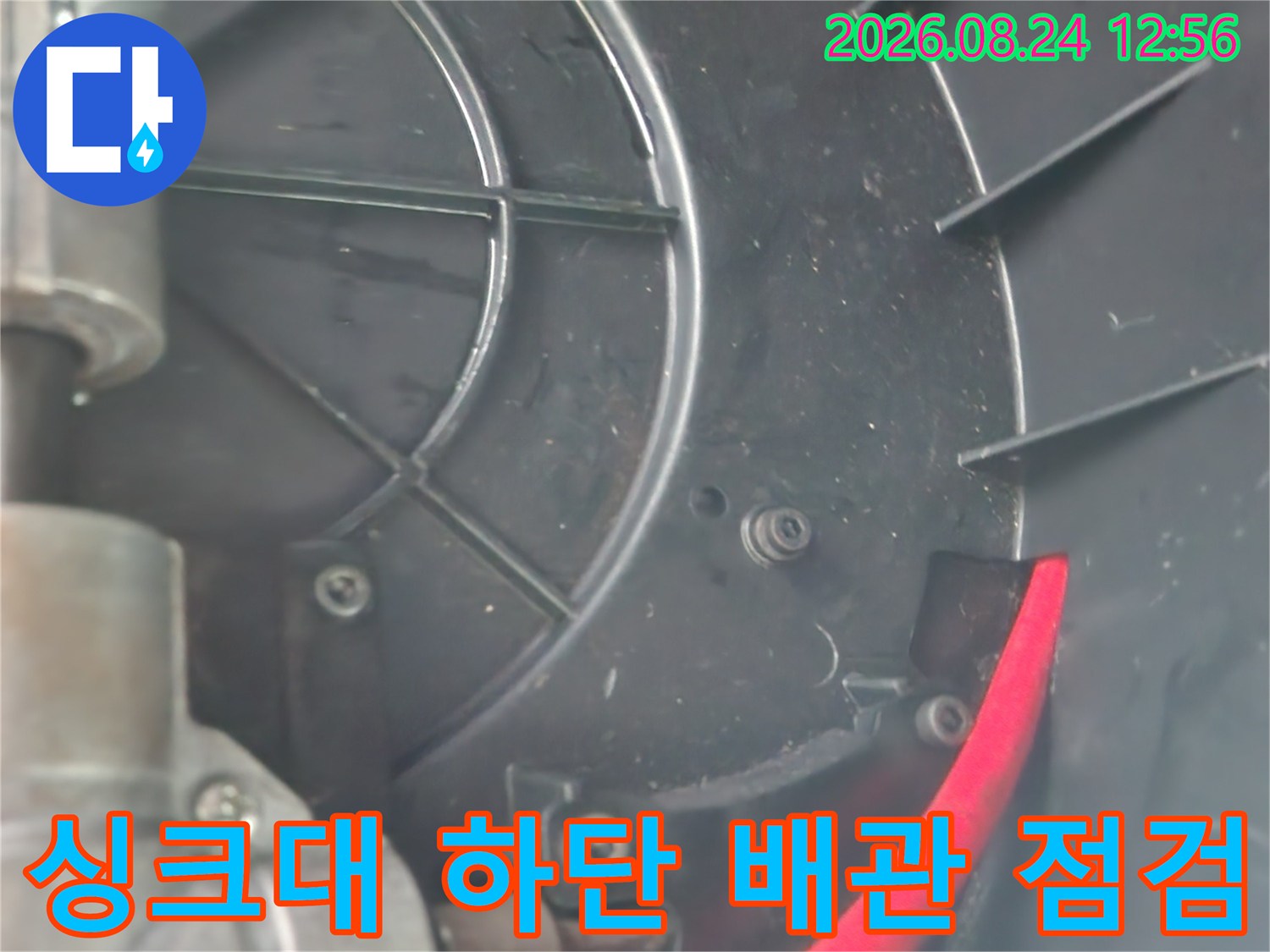 빨간색 호스가 연결된 싱크대 하부 배관 구조물