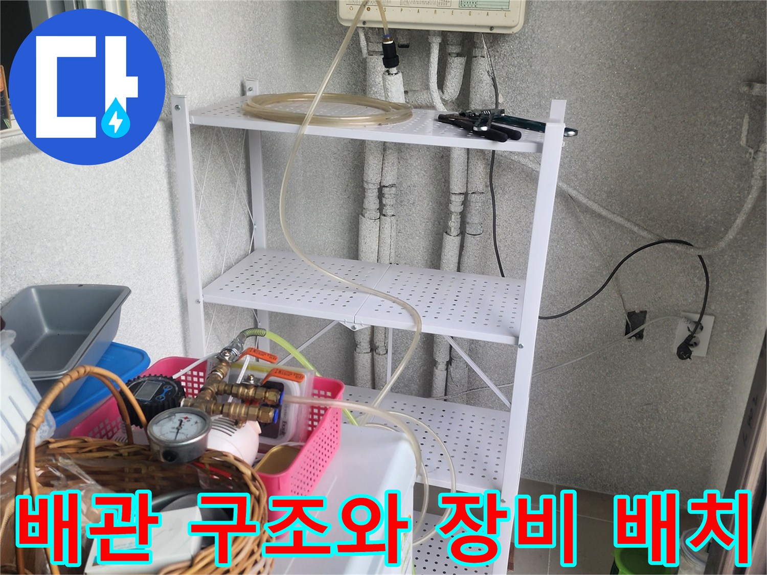 주방 하부장 내부-복잡하게 얽힌 배관 사이로 작업 도구가 배치된 상태