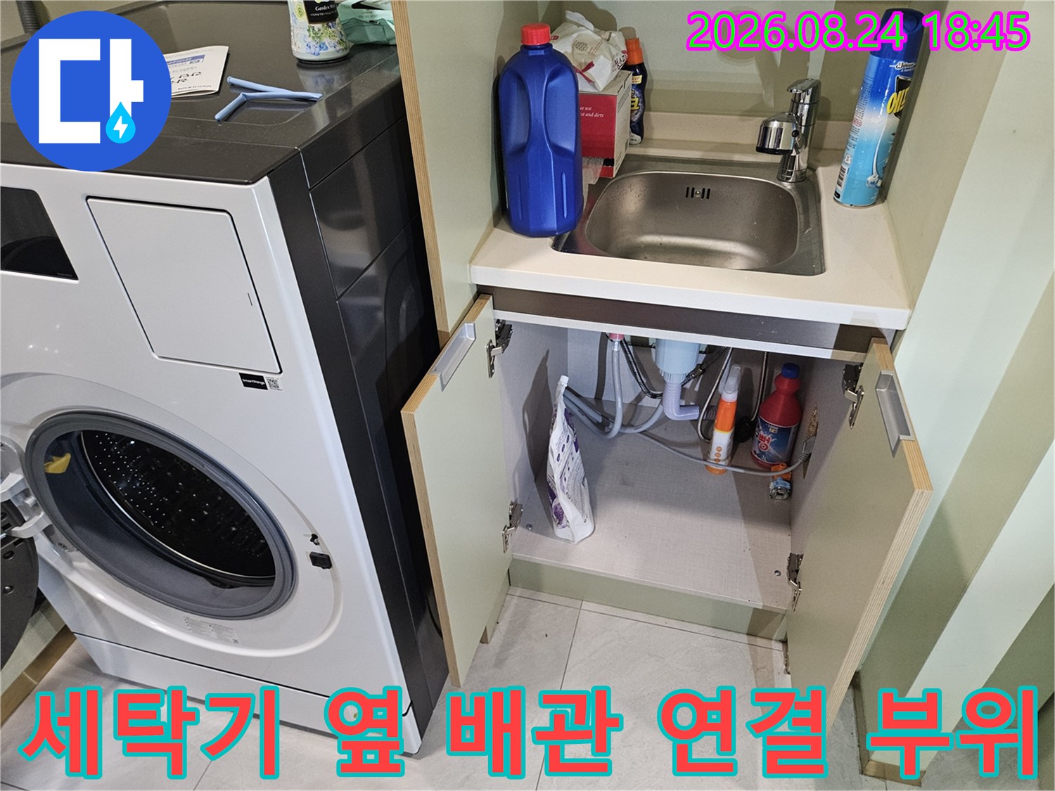 세탁실 수납장 내부의 수도 호스와 세제 용기들이 보이는 모습