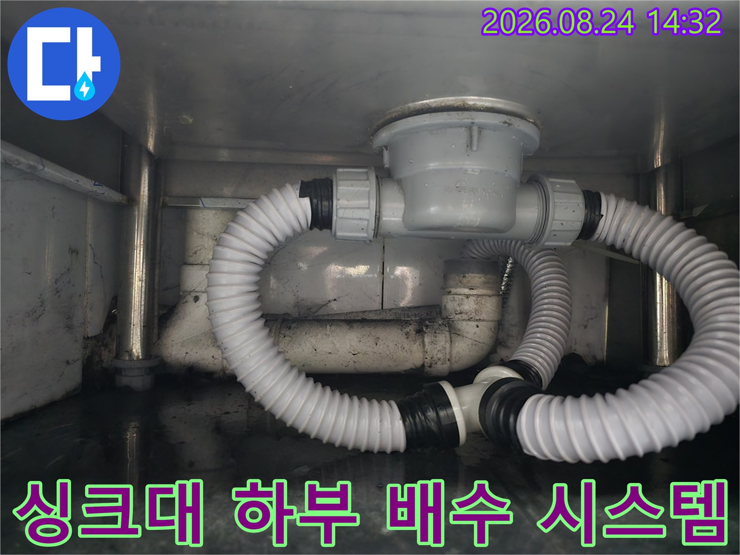 복잡하게 얽힌 싱크대 아래쪽의 흰색 주름관과 배수통 구조물입니다.