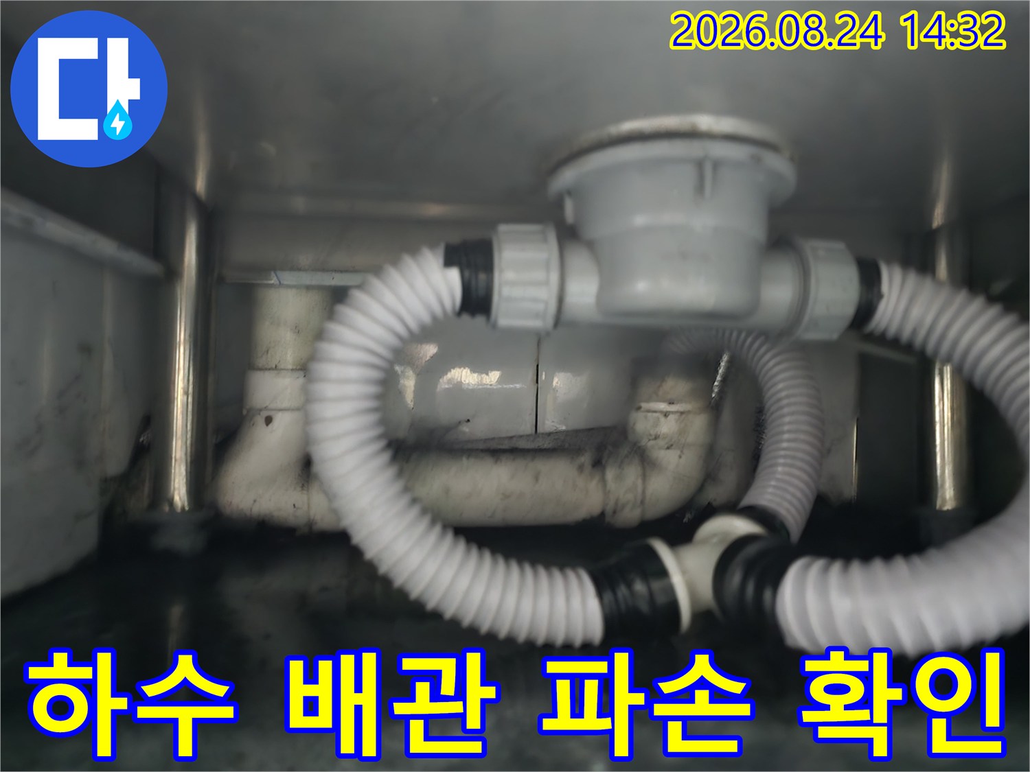 싱크대 하단 PVC 배관의 연결 부위와 굴곡진 배수 호스 모습