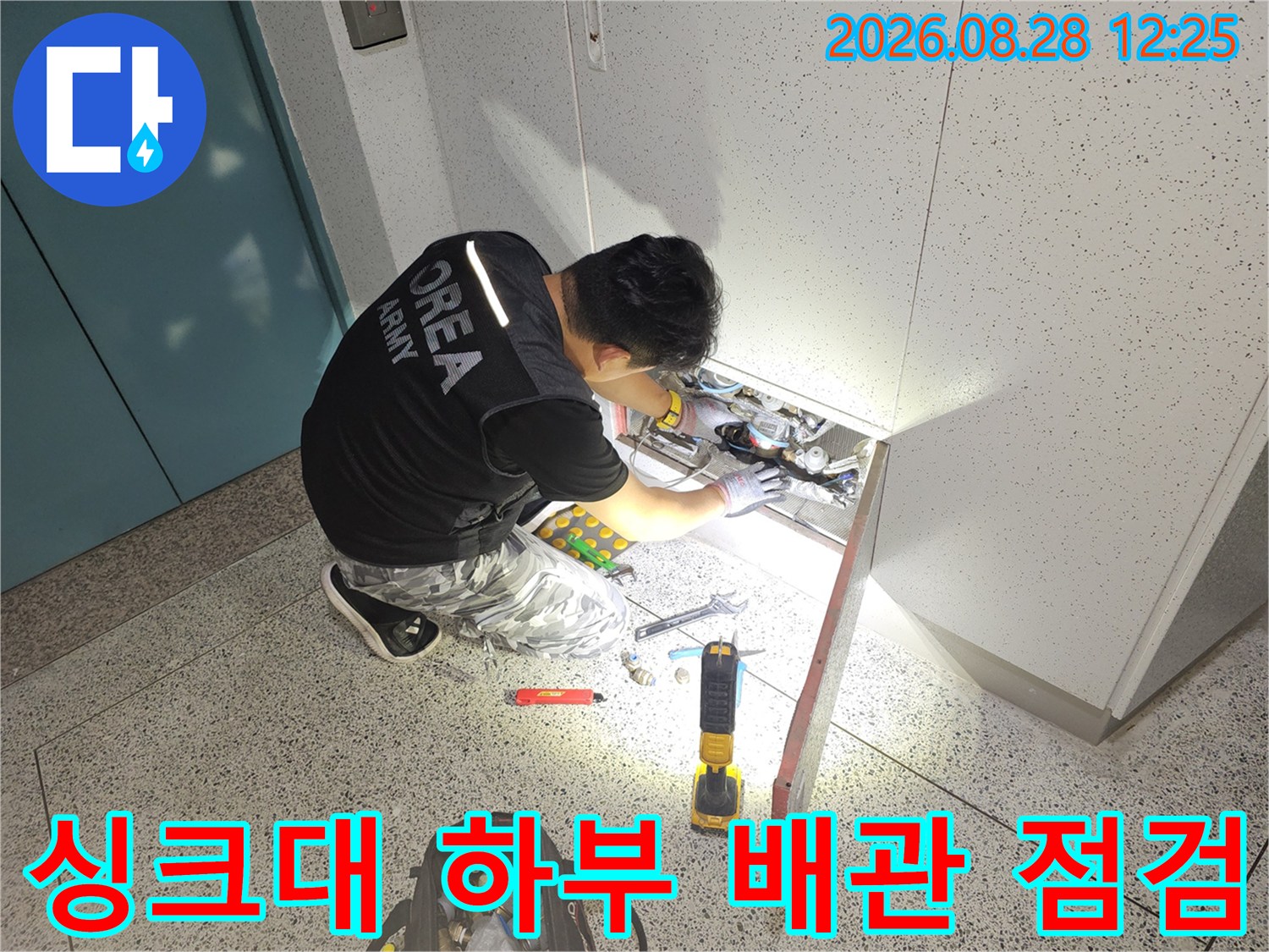 싱크대 밑 공간에서 배관의 누수 여부를 확인하기 위해 집중적으로 작업하는 모습입니다.