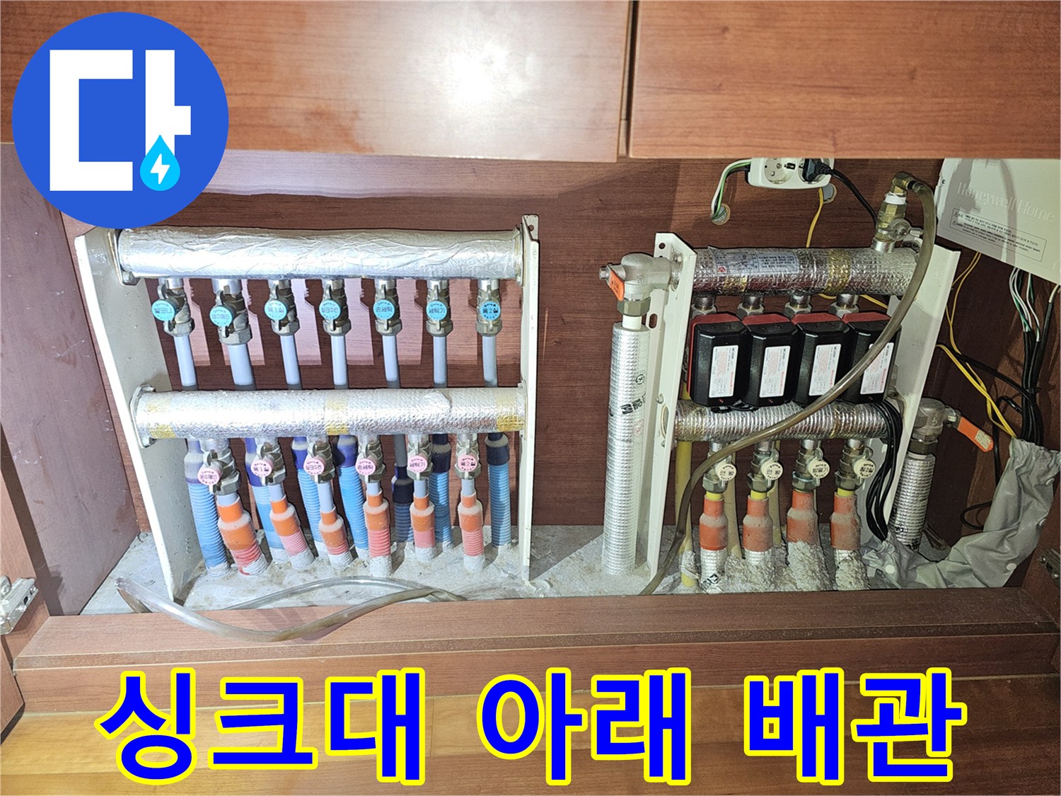 싱크대 밑 분배기와 은색 보온재로 덮인 다수의 배관들