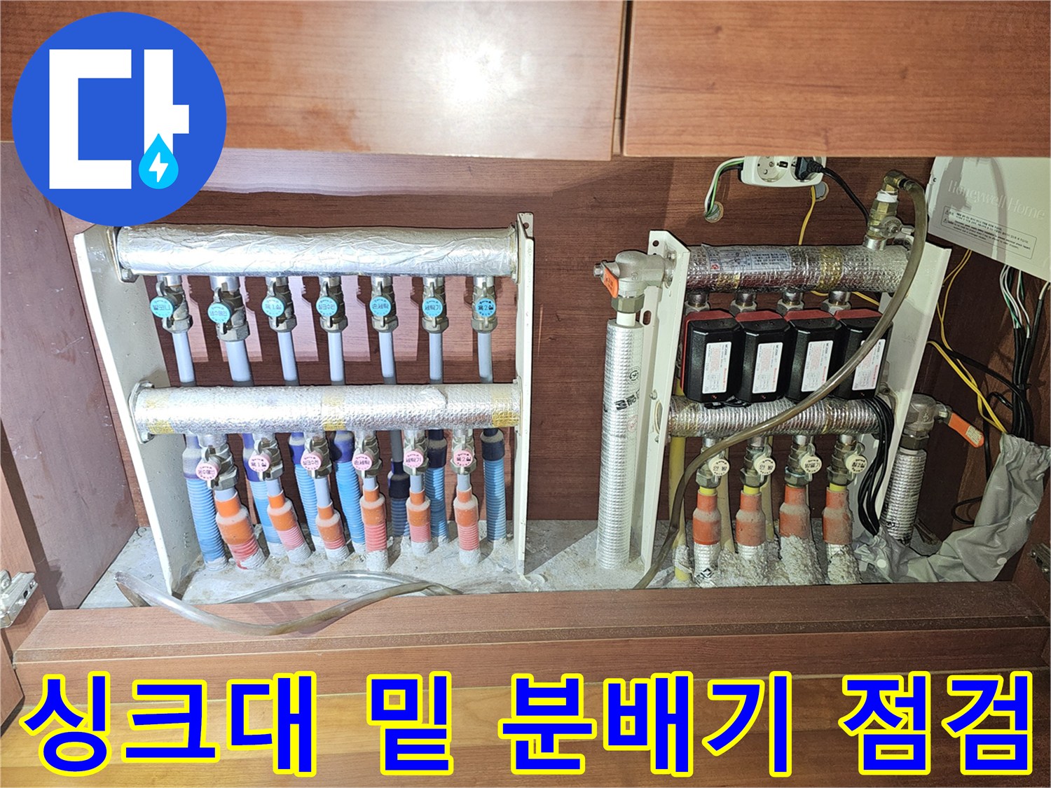 주방 싱크대 하단부에 위치한 배관 분배기와 밸브들의 모습