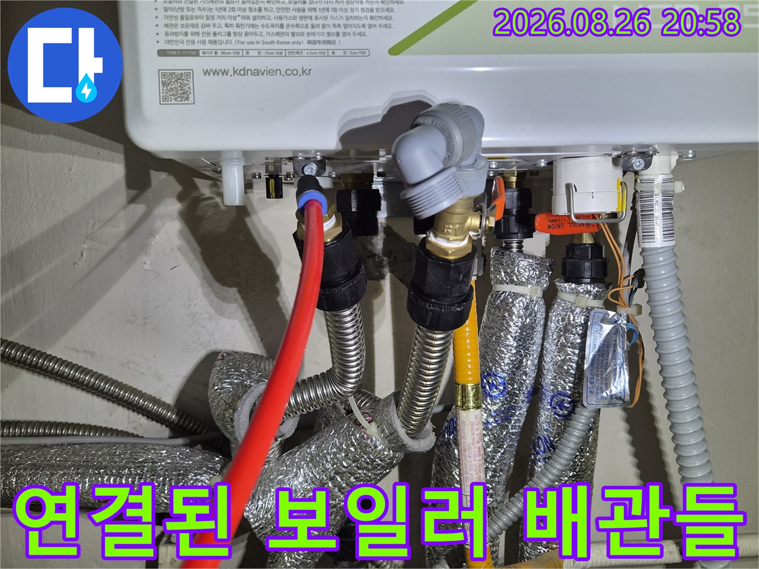 보일러 하단의 금속 부품과 은박 배관의 연결 모습입니다.