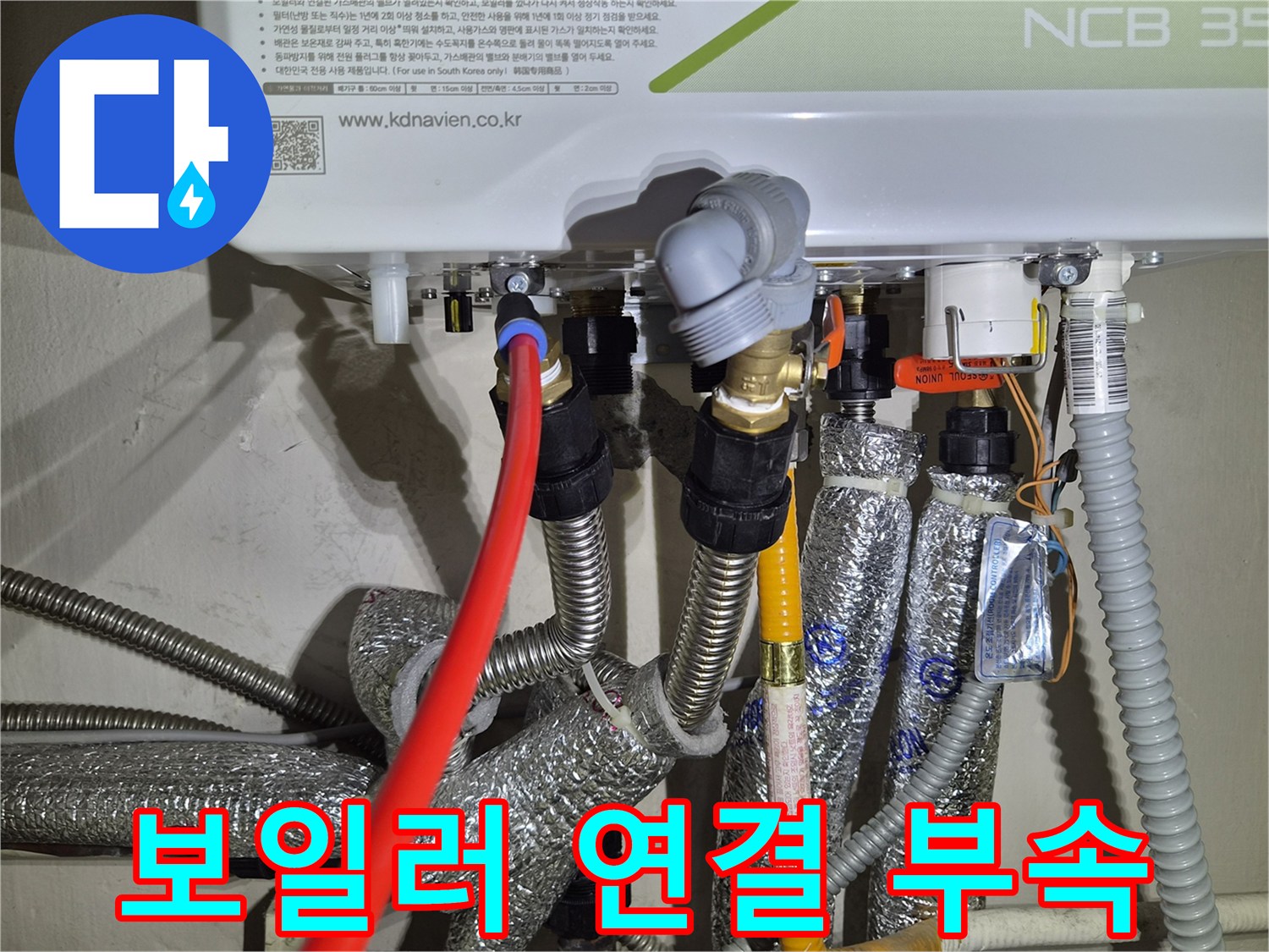 보일러 하단의 은색 보온재와 황동 재질의 배관 연결 부위