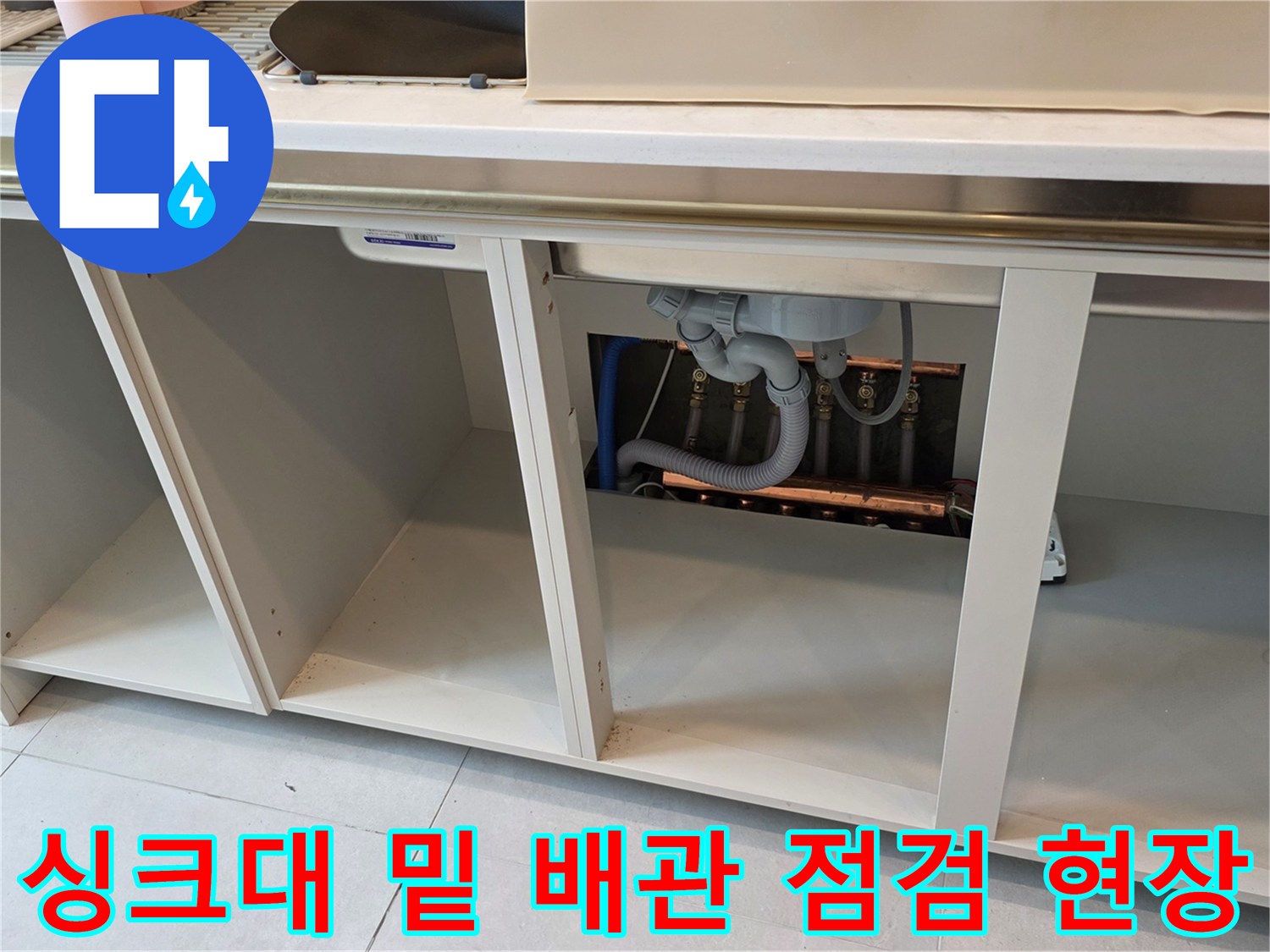 주방 싱크대 하단-노출된 배관의 연결 상태를 정밀 점검하는 중입니다.