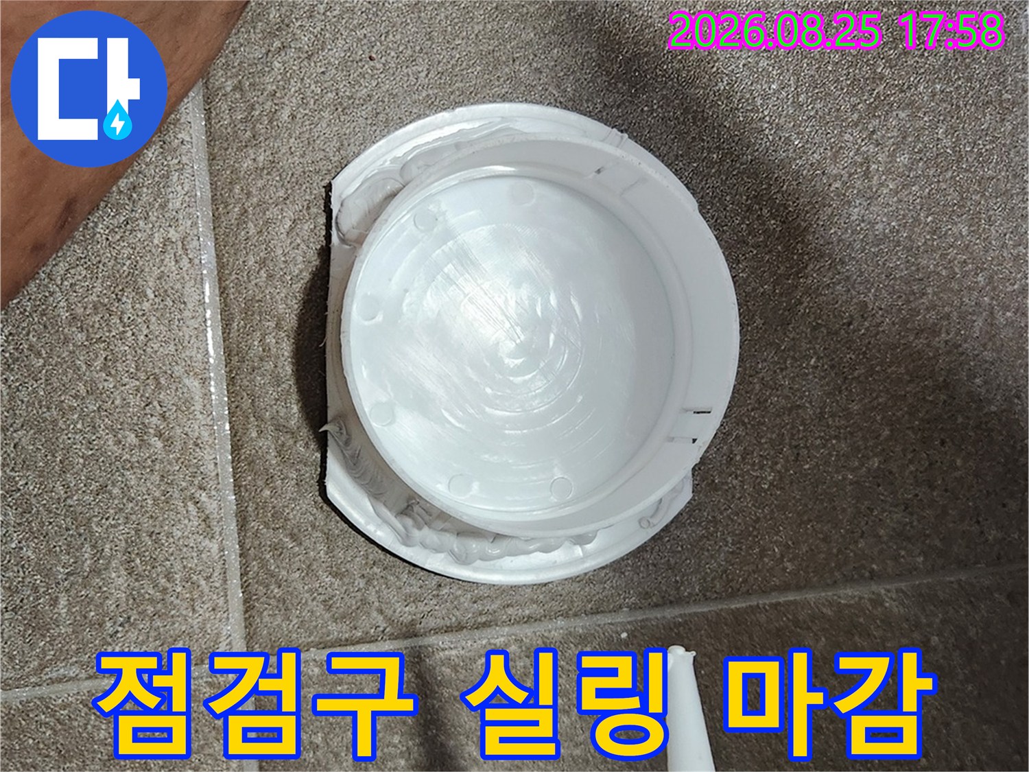 하얀색 점검구 가장자리에 실리콘을 도포하고 있습니다
