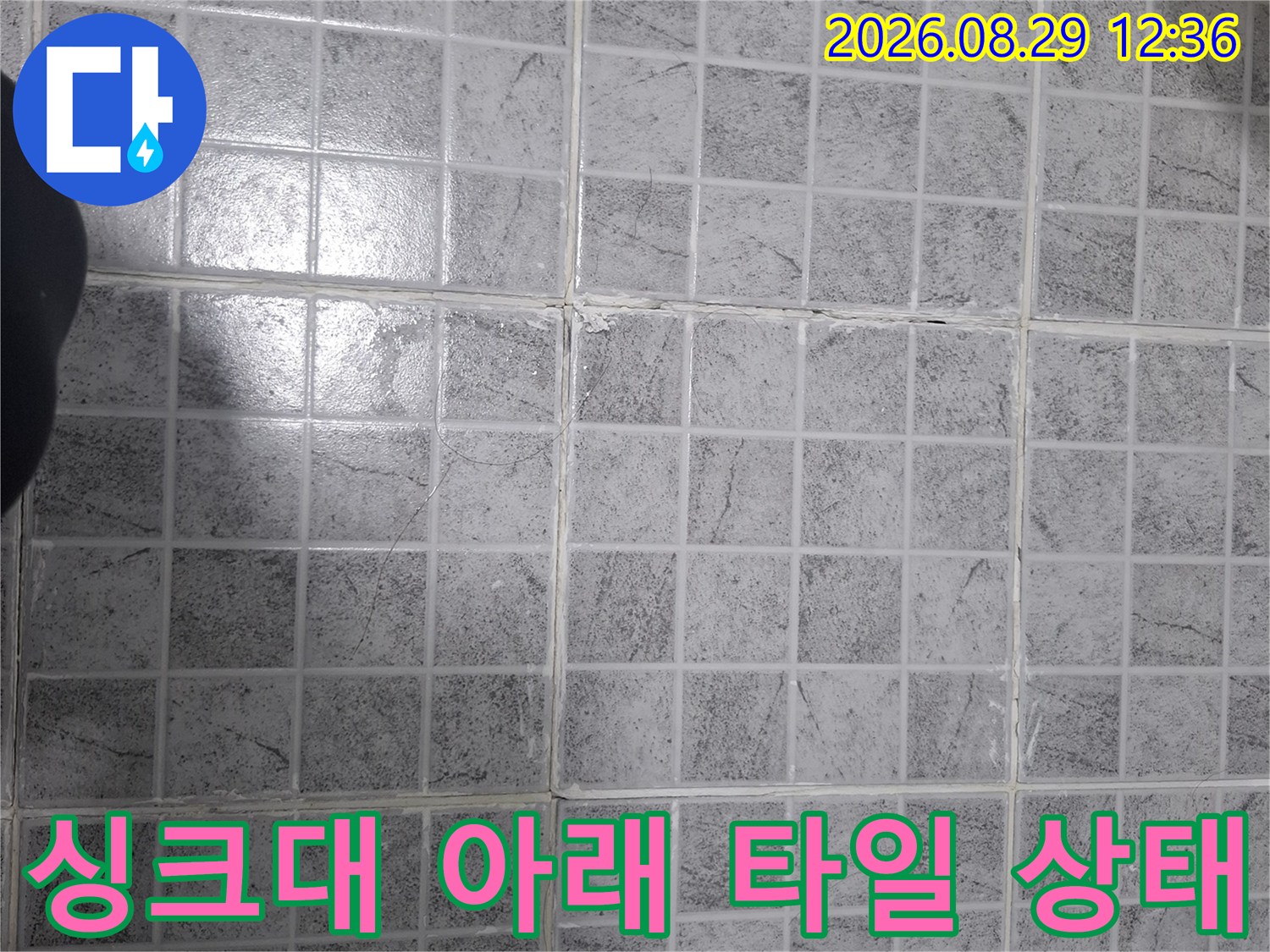 싱크대 하부장 근처의 타일 바닥면을 촬영한 사진입니다.