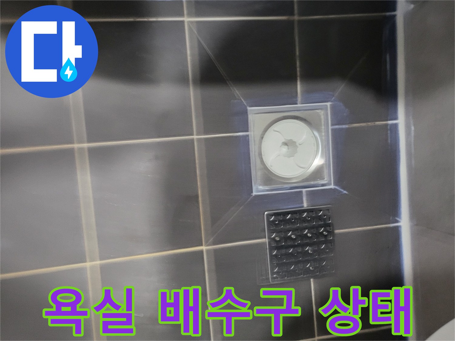 어두운 색상의 욕실 타일과 배수구 유가 모습