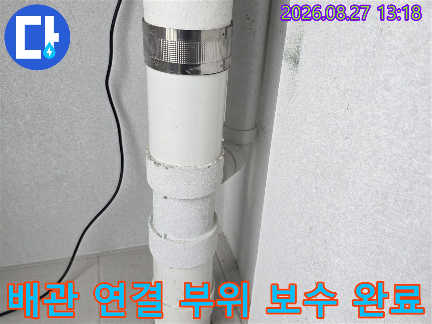 우수관의 하얀색 배관과 은색 금속 클램프가 체결된 모습