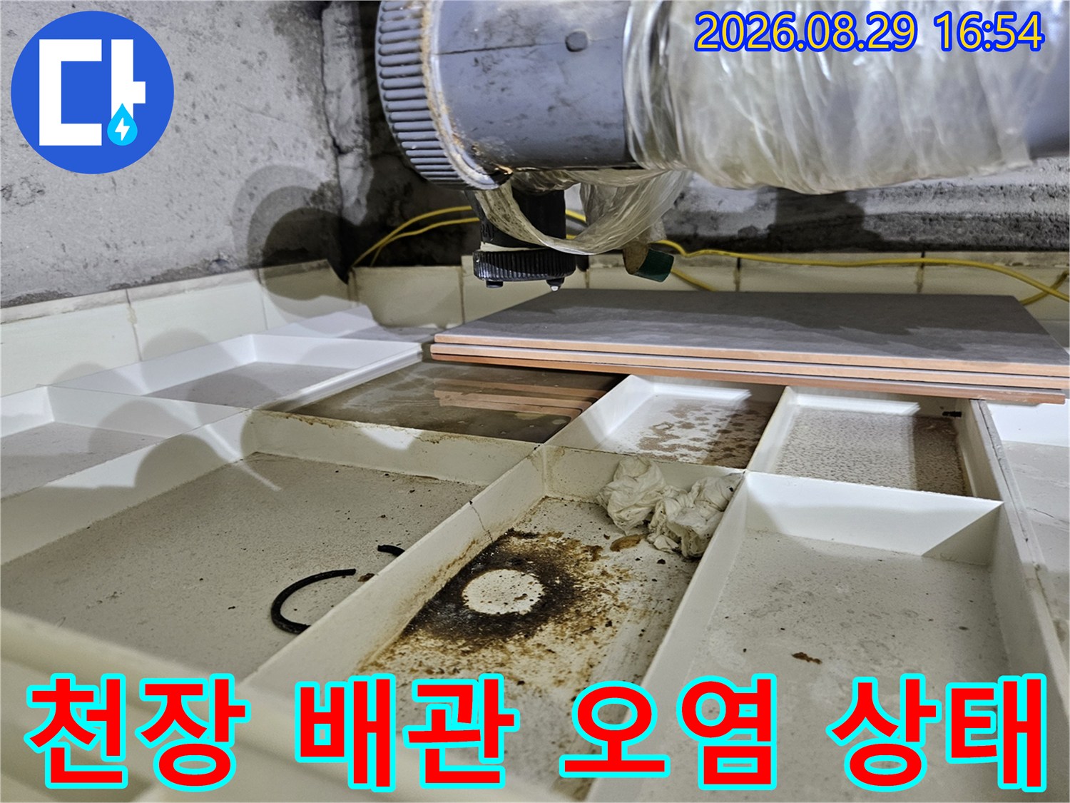 천장 내부의 젖은 배관과 얼룩진 마감재를 나타내는 사진입니다.